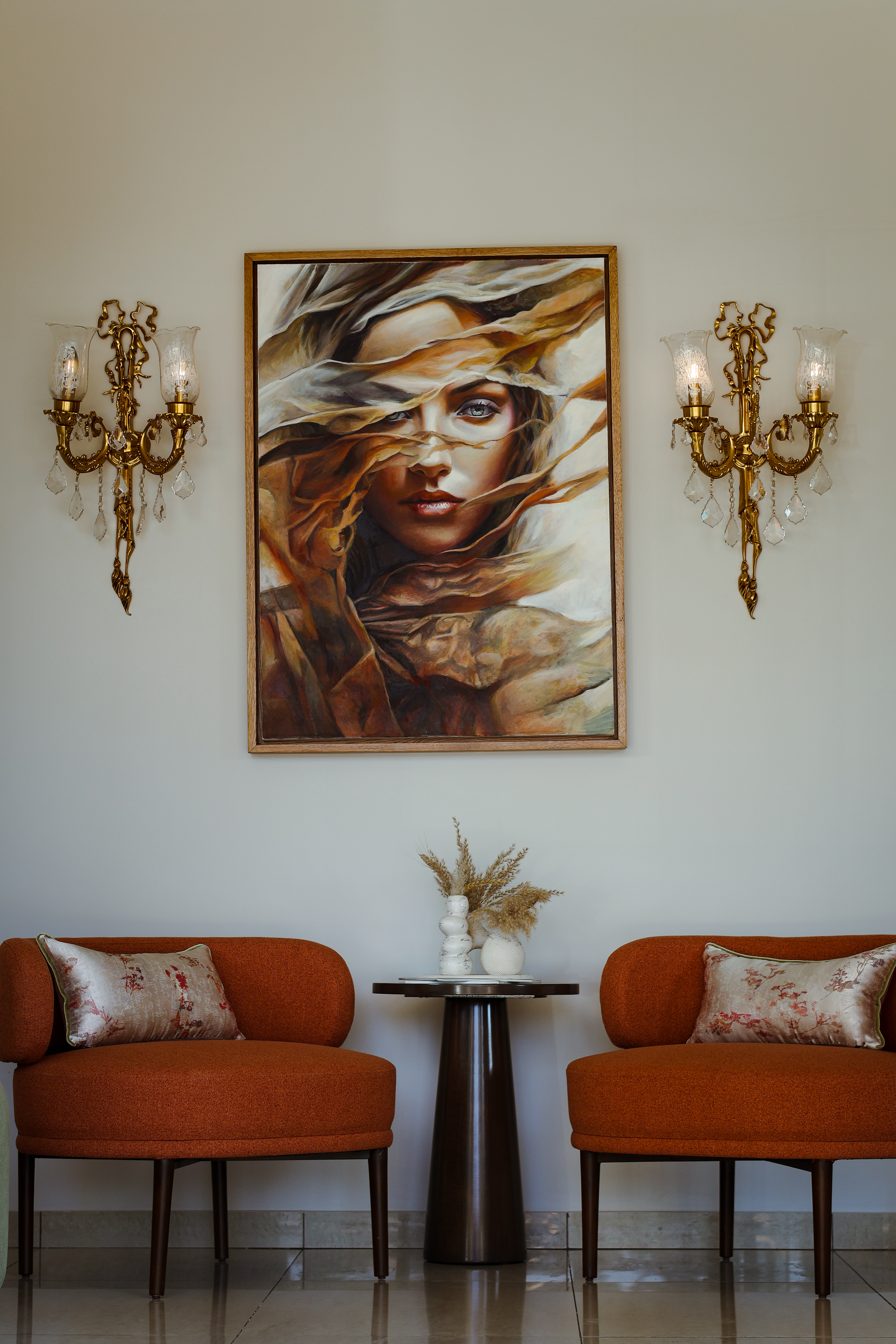 Sophisticated interior with abstract portrait, orange chairs, and luxurious decor elements.