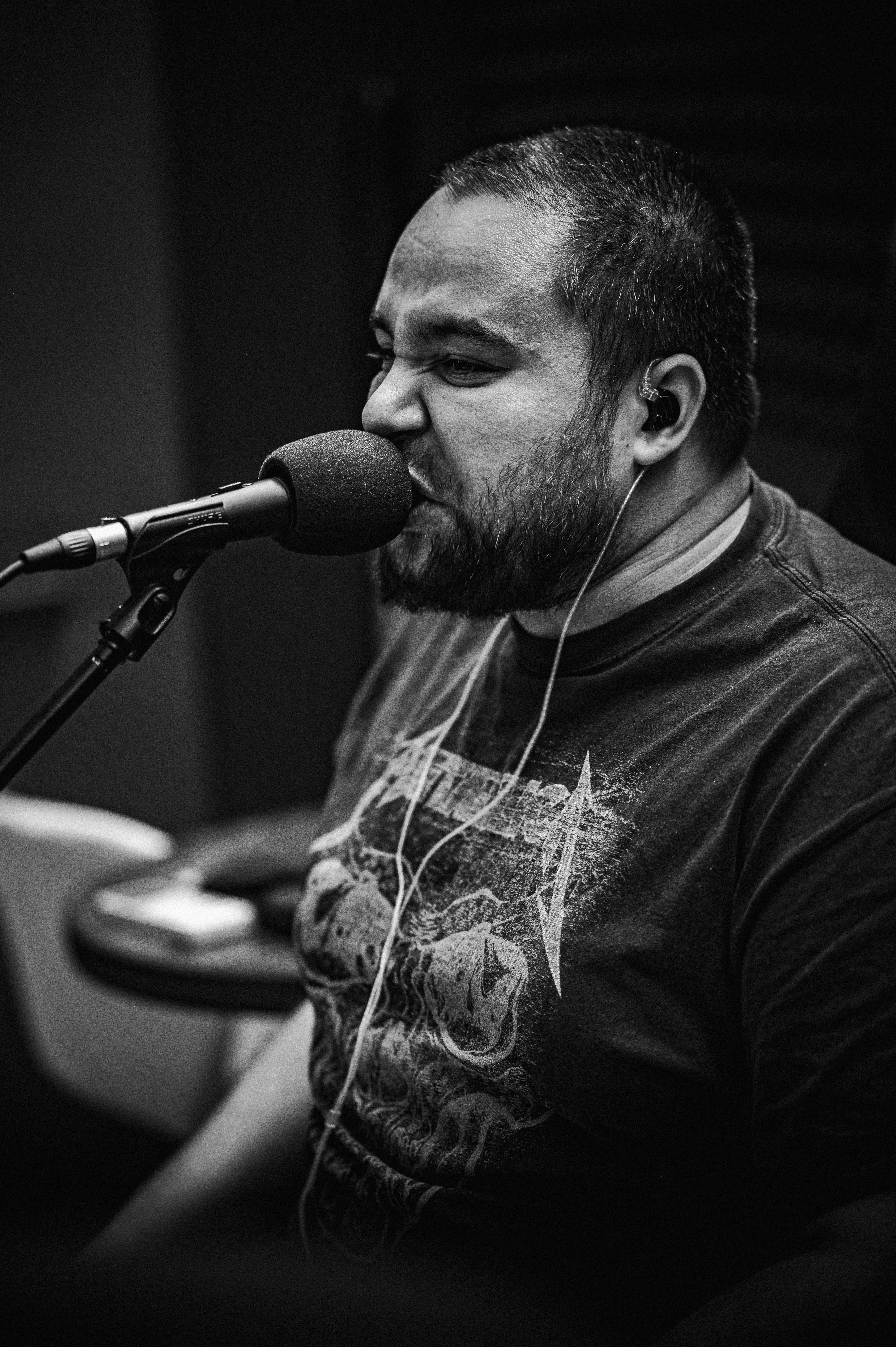 Bearded man passionately singing into a microphone in a studio.