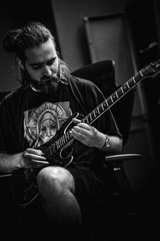 Moody black and white portrait of a guitarist playing in a studio setting.