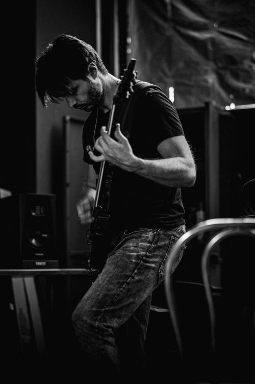 Free Black and white portrait of a guitarist immersed in playing indoors. Stock Photo