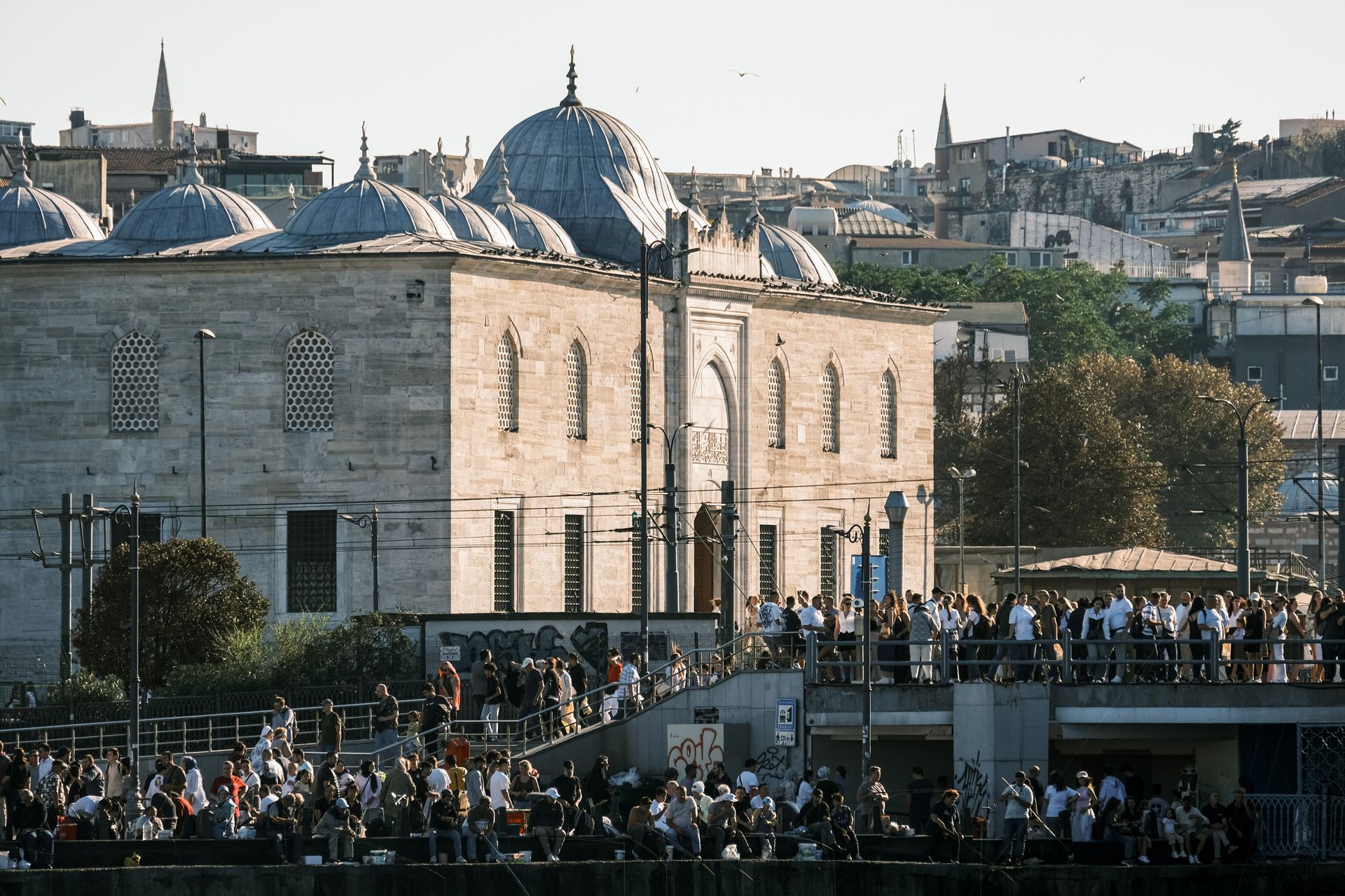 A bustling crowd gathers outside a historic mosque in Istanbul, capturing urban life and architecture.