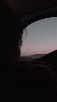 一名女子在车里静静地看着日落，捕捉巴西风景上空渐变的天空