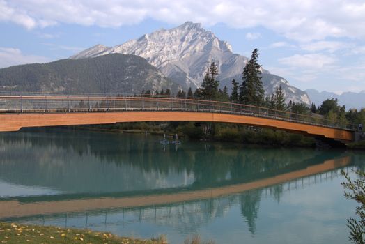 Peaceful view of a bridge with mountain reflections in Banff, Alberta.