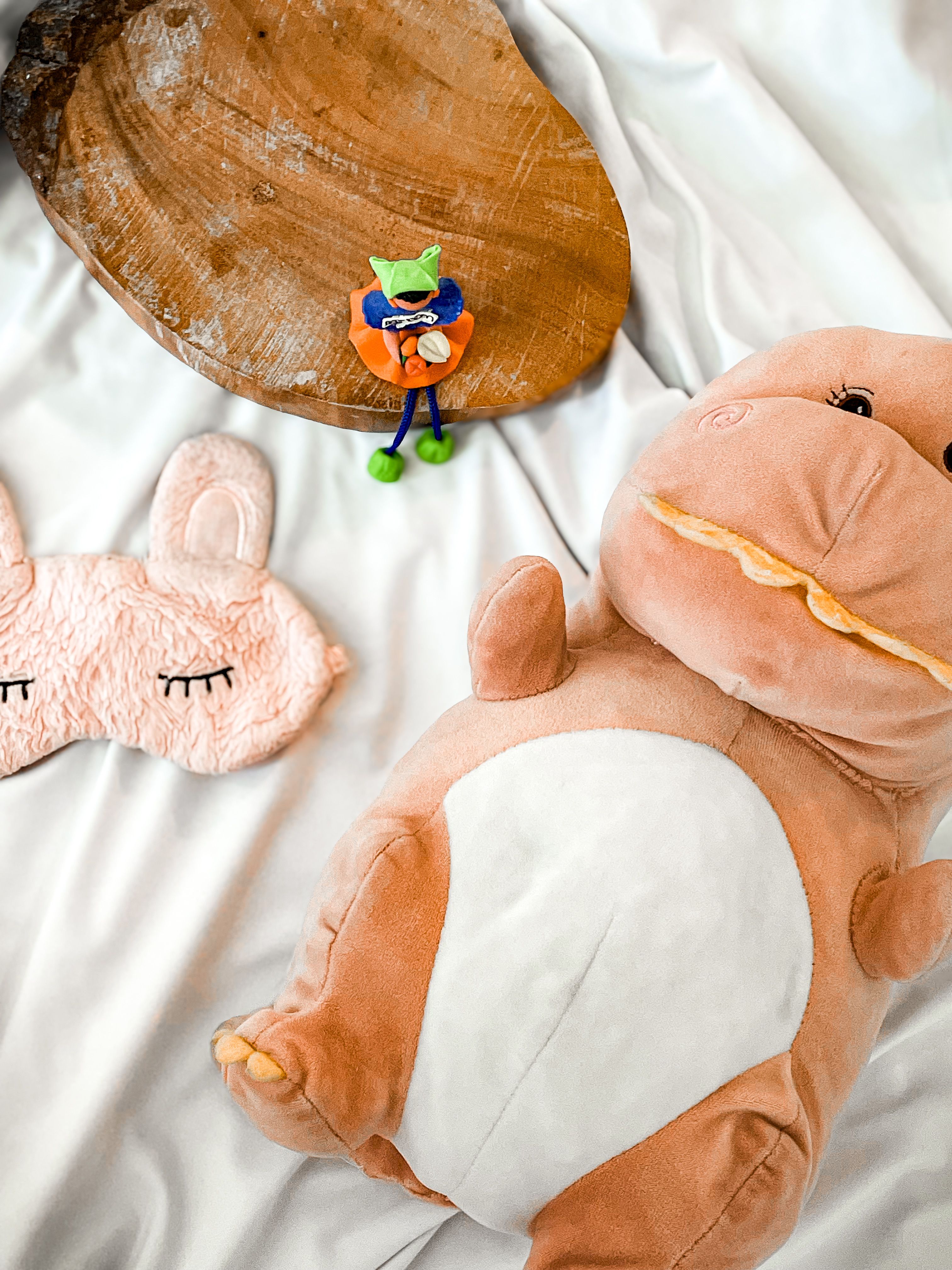 Cute plush toys and a sleeping mask on a cozy white blanket, perfect for child decor.