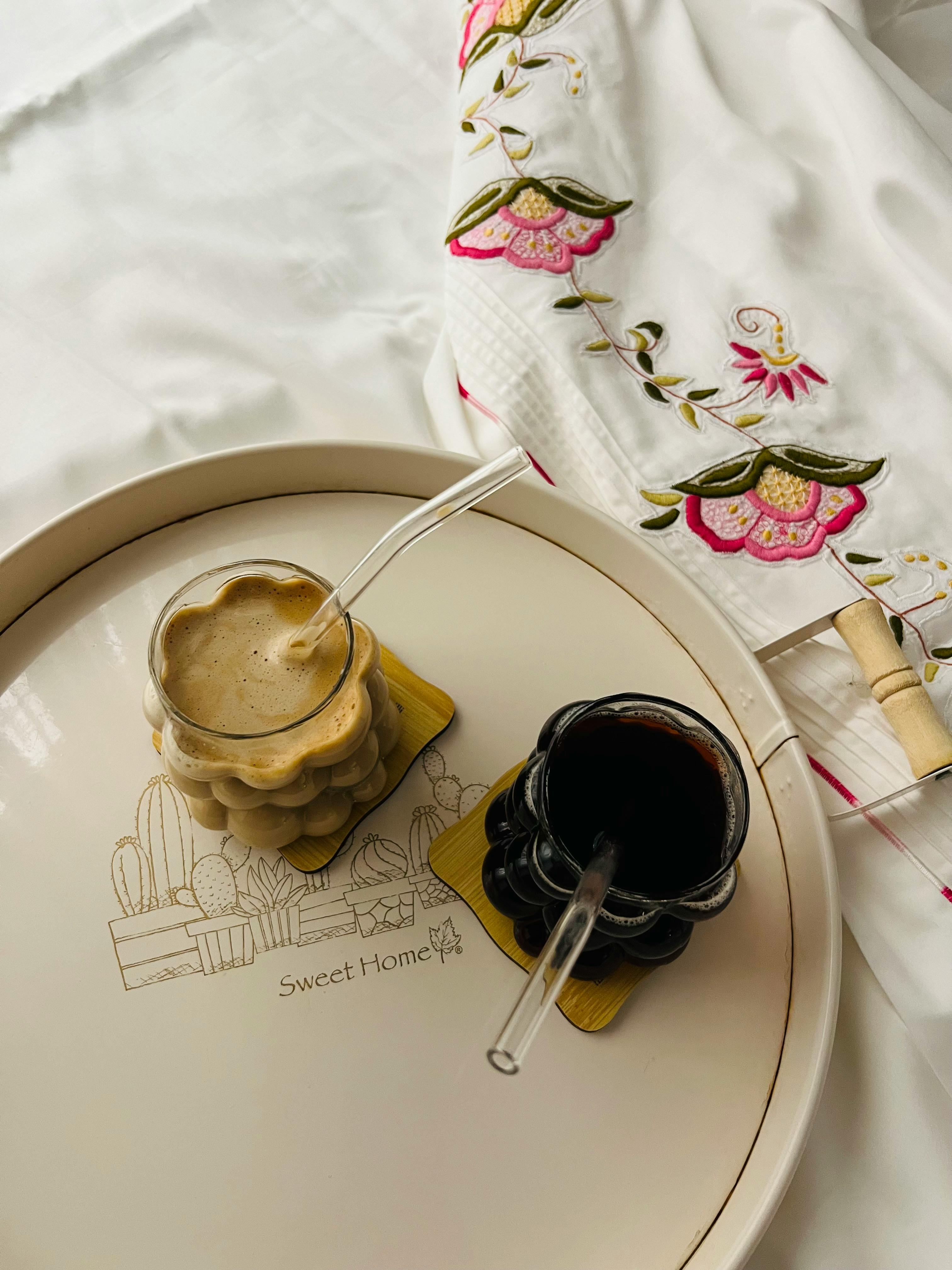 Elegant coffee drinks on a stylish tray with embroidered cloth, perfect for cozy mornings.