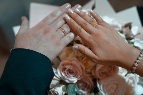 Free Hands with wedding rings over a bouquet of pink roses, symbolizing love and commitment. Stock Photo