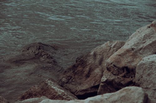 Free A calming view of a rocky shoreline with gentle water waves, evoking a peaceful mood. Stock Photo