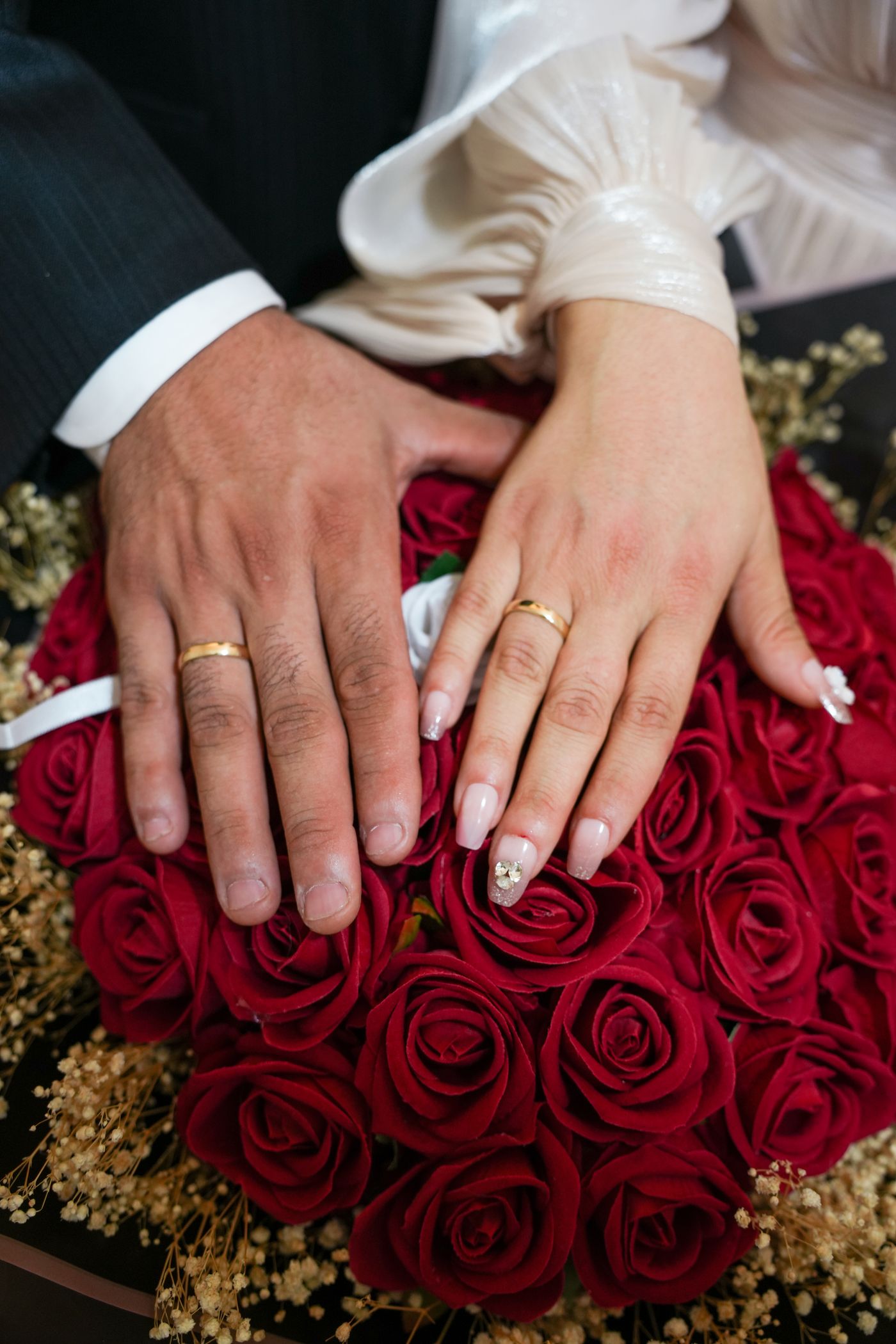 Wedding rings resting among deep red roses