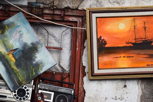 A collection of vintage paintings and radios mounted on a rustic wall, showcasing artistic and antique charm.