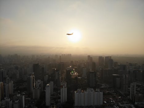 A stunning aerial view of São Paulo with an airplane flying over the city during sunset.