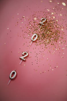 粉色背景上点缀着2020年蜡烛和金色五彩纸屑，营造出非常适合派对主题的节日氛围