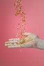 粉红色背景下，张开的手上倾泻着金色五彩纸屑