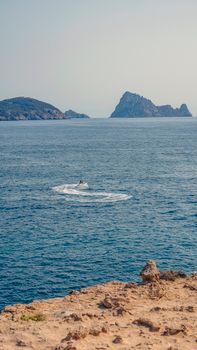 A serene ocean view featuring a small boat and distant rocky islands under a clear sky.