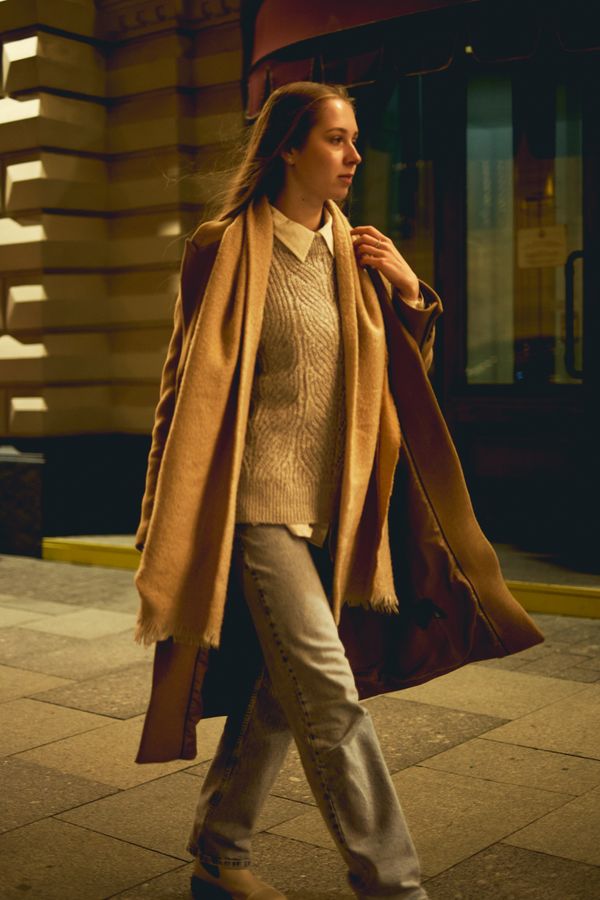 Woman in a camel coat over a neutral knit sweater