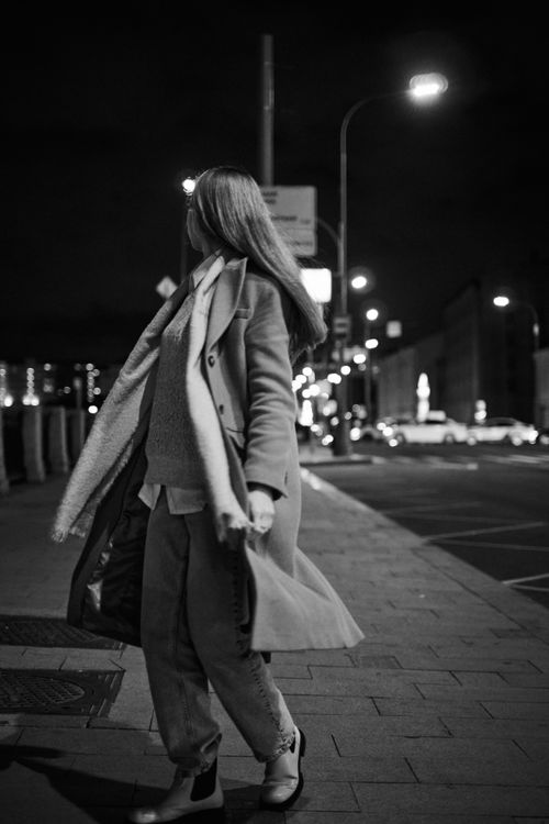 Free Black and white photo of a fashionable woman walking down a city street at night. Stock Photo