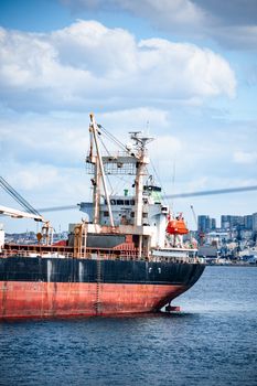 A cargo ship sailing in the Bosphorus with Istanbul's urban skyline in the background.