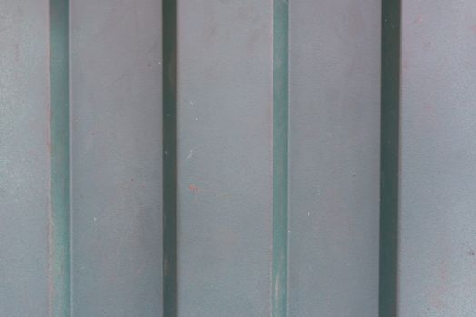 Detailed close-up of a weathered metal surface featuring vertical shadows.