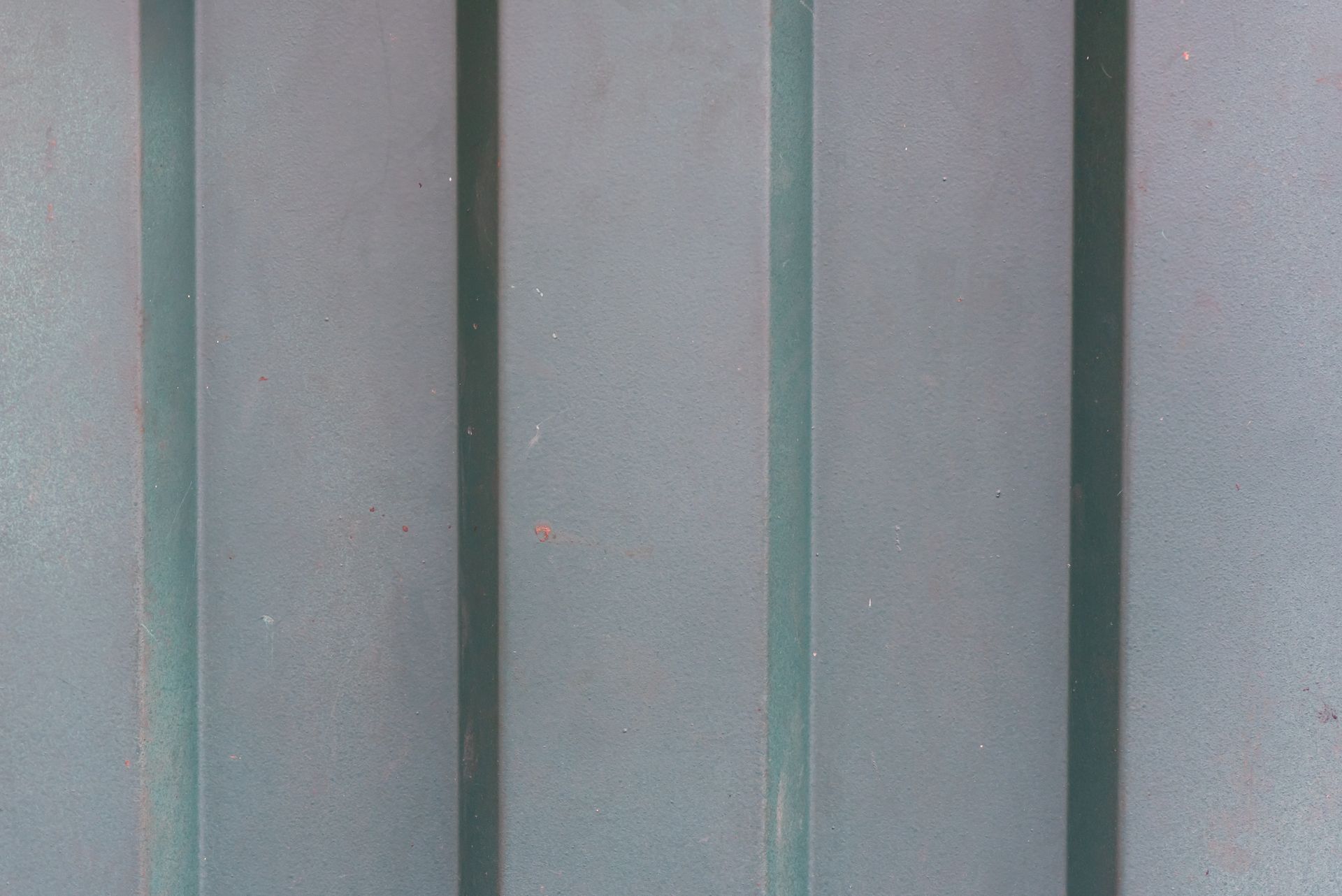 Detailed close-up of a weathered metal surface featuring vertical shadows.
