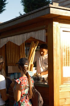 Vendor serving ice cream at a wooden outdoor stand during the day.