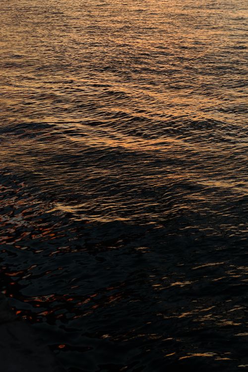 Free Serene view of golden sunset reflecting on calm ocean waters. Stock Photo