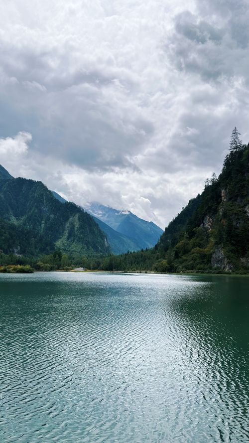 Free Tranquil lake with mountainous backdrop in Ngawa, China, under dramatic skies. Stock Photo