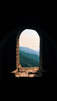 Scenic view through a Great Wall archway with lush mountains and valleys.