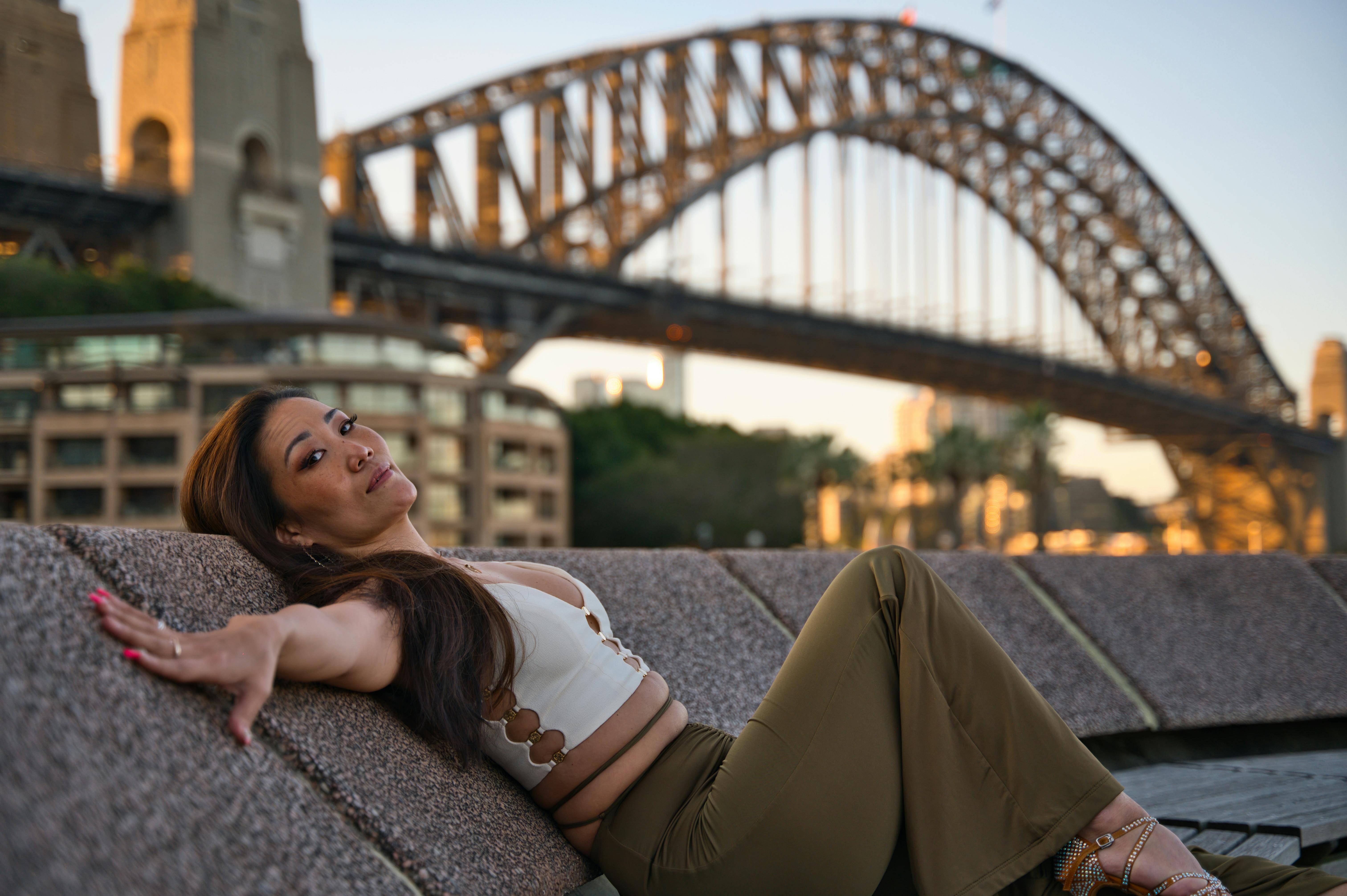 Captivating portrait of a dancer reclining in front of Sydney's iconic Harbor Bridge during sunset.