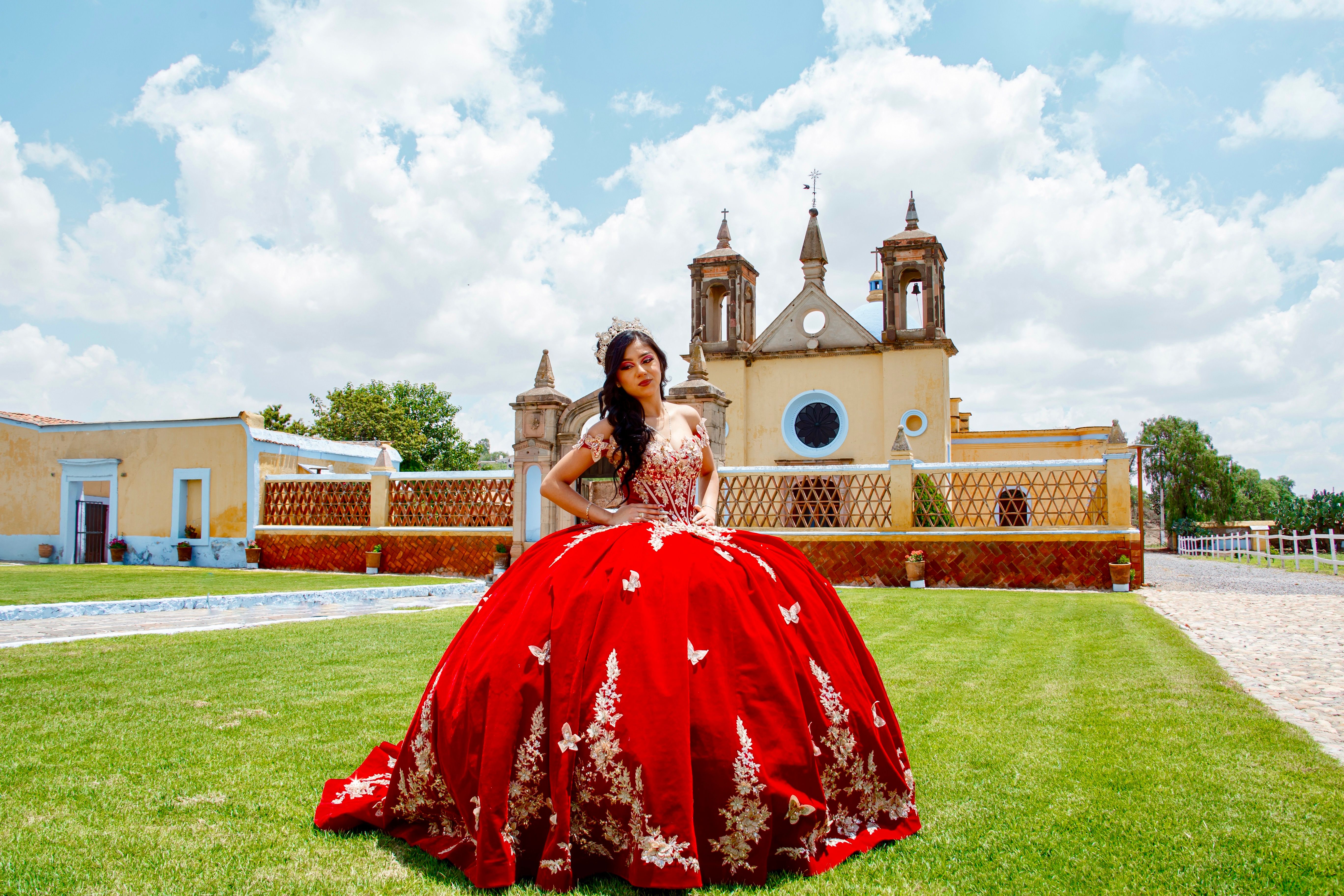 Young woman celebrating quinceañera in vibrant red dress outdoors in Mexico.