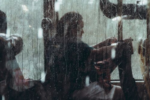 Free Silhouette of a person seen through a rain-streaked bus window. Moody and reflective scene. Stock Photo