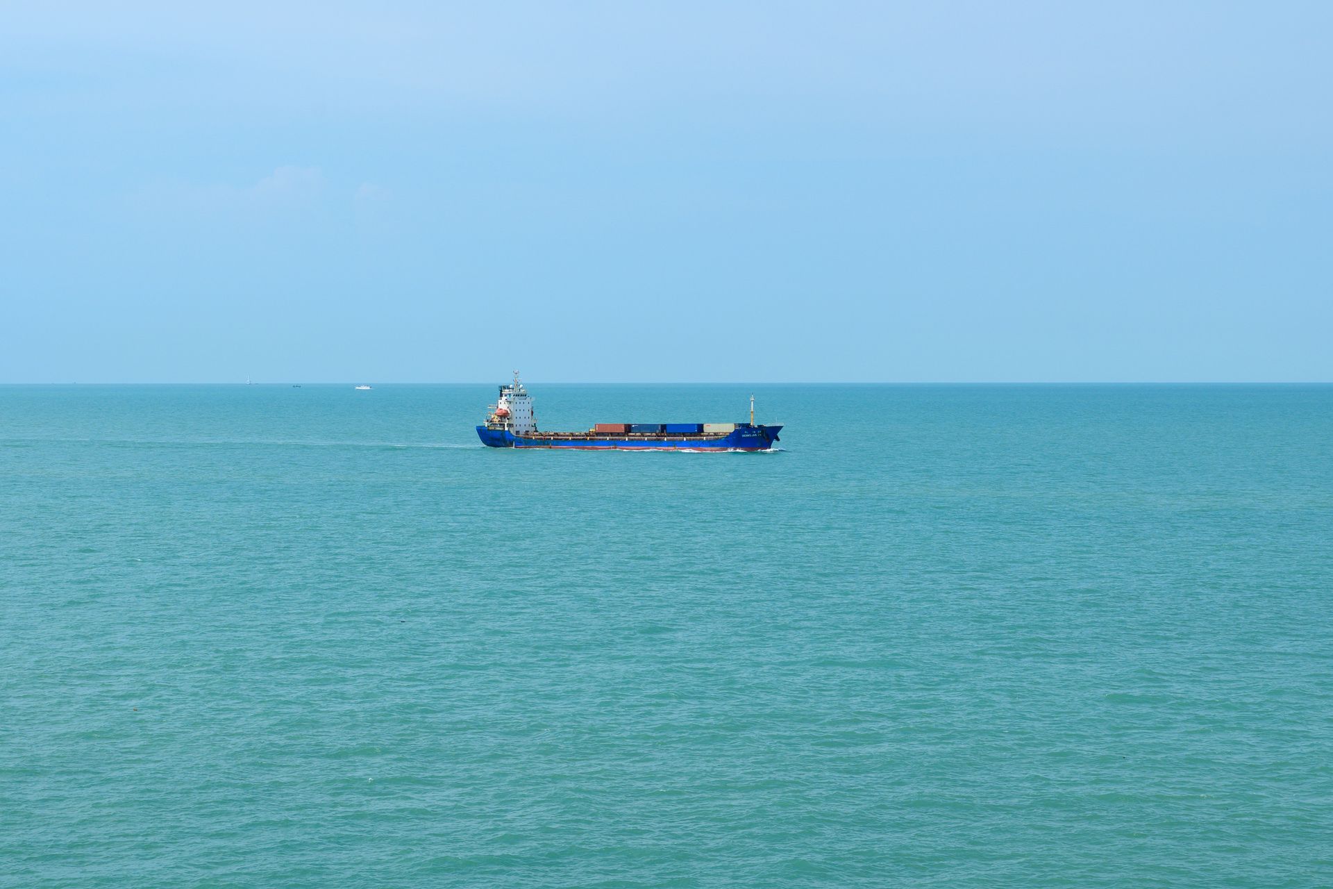 A cargo ship sailing across the Mediterranean Sea at the horizon