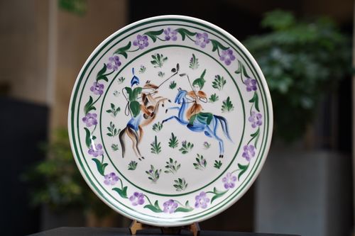 Free Ornate ceramic plate featuring colorful hand-painted horsemen and floral motifs. Stock Photo