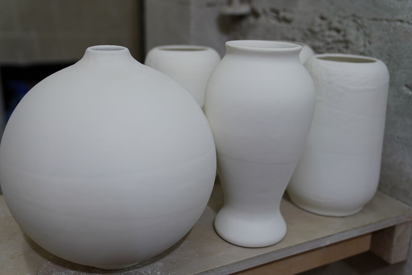 Unglazed white ceramic vessels drying on a studio shelf — photo by Tahir Xəlfəquliyev on Pexels