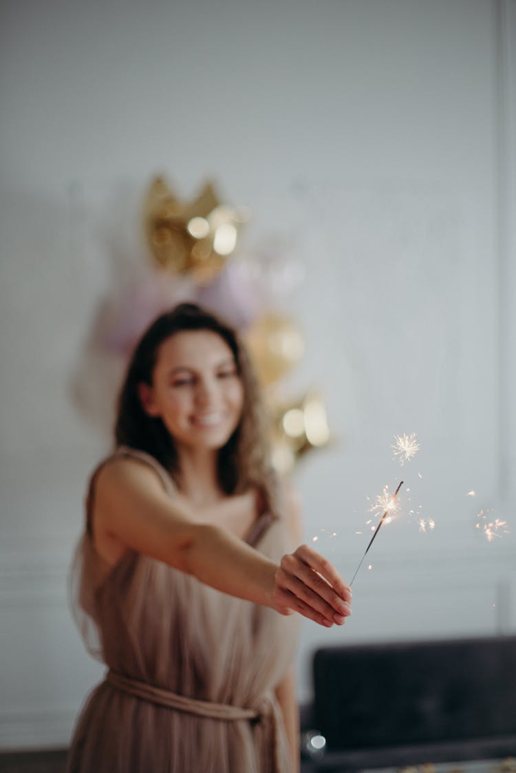 Shallow Focus Photo Of Woman In Brown Sleeveless Dress Holding Sparkle