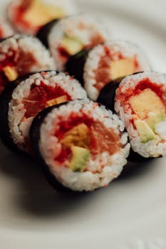 Tasty sushi rolls with salmon, avocado, and rice wrapped in seaweed on a plate.