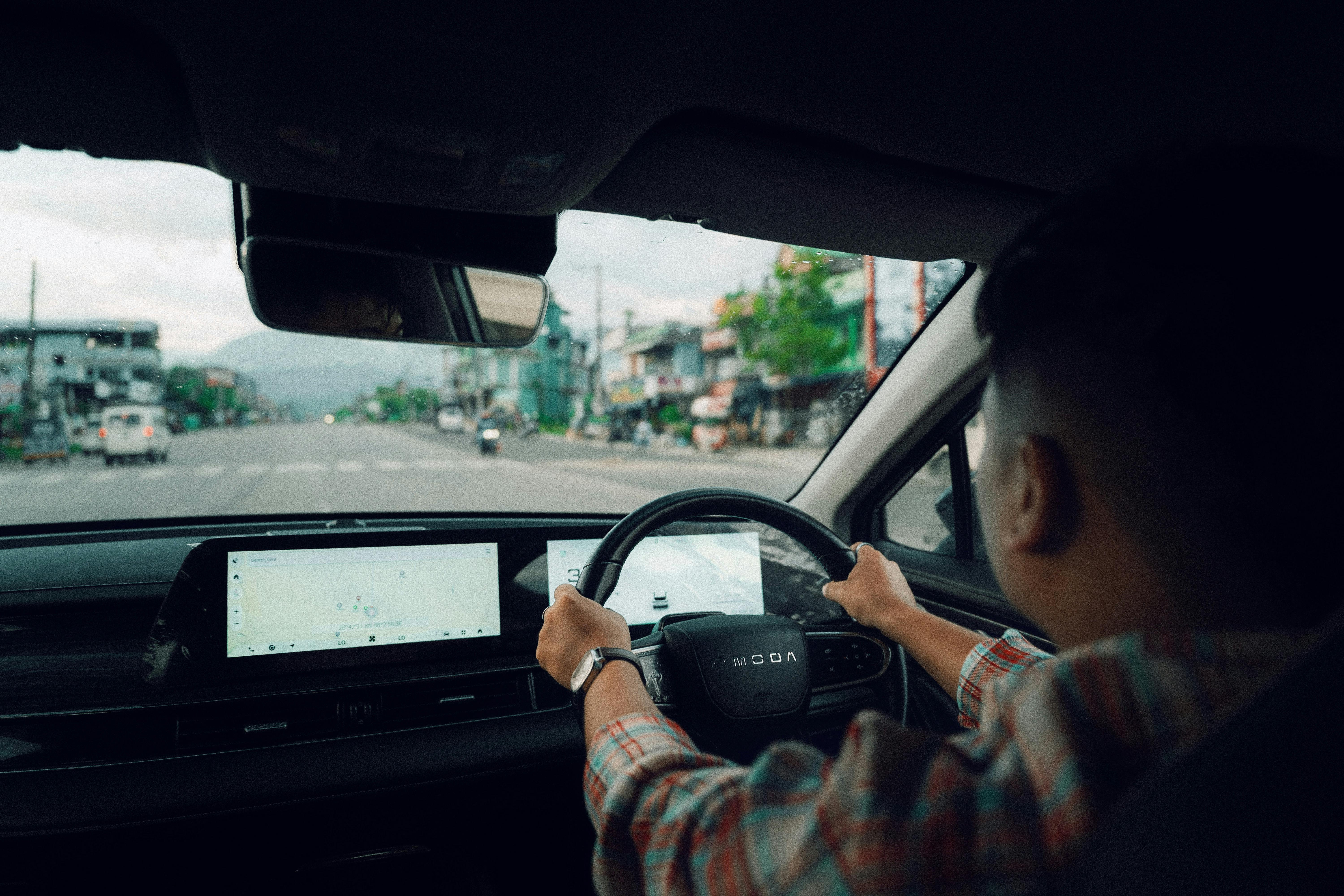 Driving Scene With A Man Confidently Navigating A Car On A Busy Road