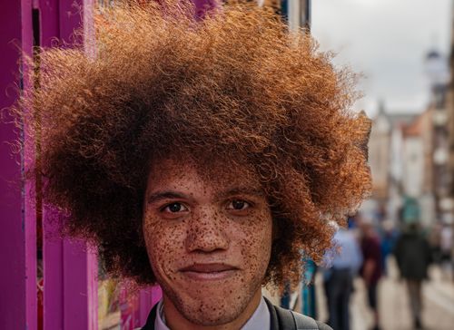 Free Close-up portrait of a young man with afro hair in the vibrant streets of Whitby, England. Stock Photo