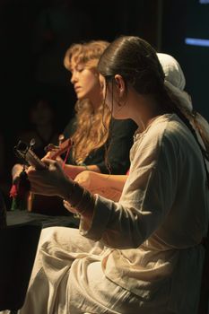Musicians performing acoustic guitar live on stage in moody lighting.