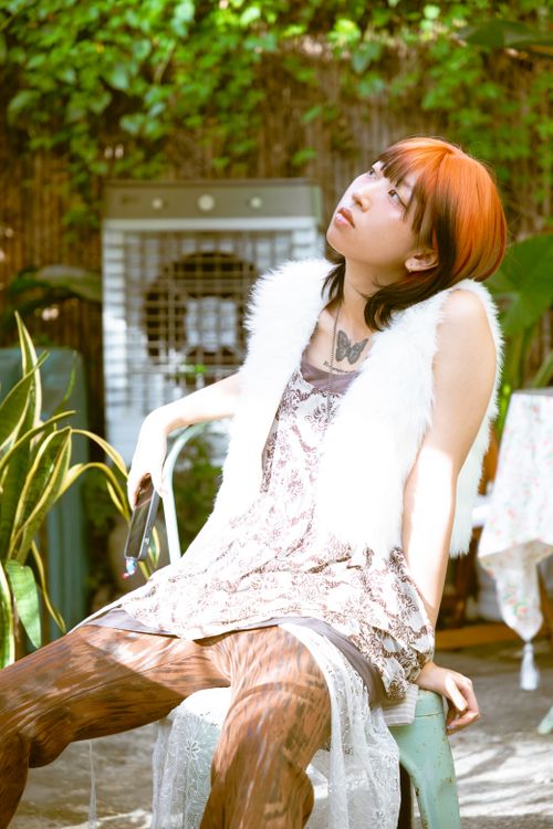 Free Young adult sitting outdoors, enjoying a sunny day with trendy fashion. Stock Photo