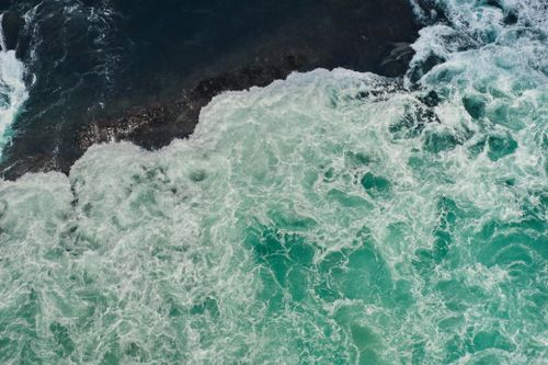 Free Dynamic aerial view of turquoise waves crashing on rocky coast in Naruto, Japan. Stock Photo