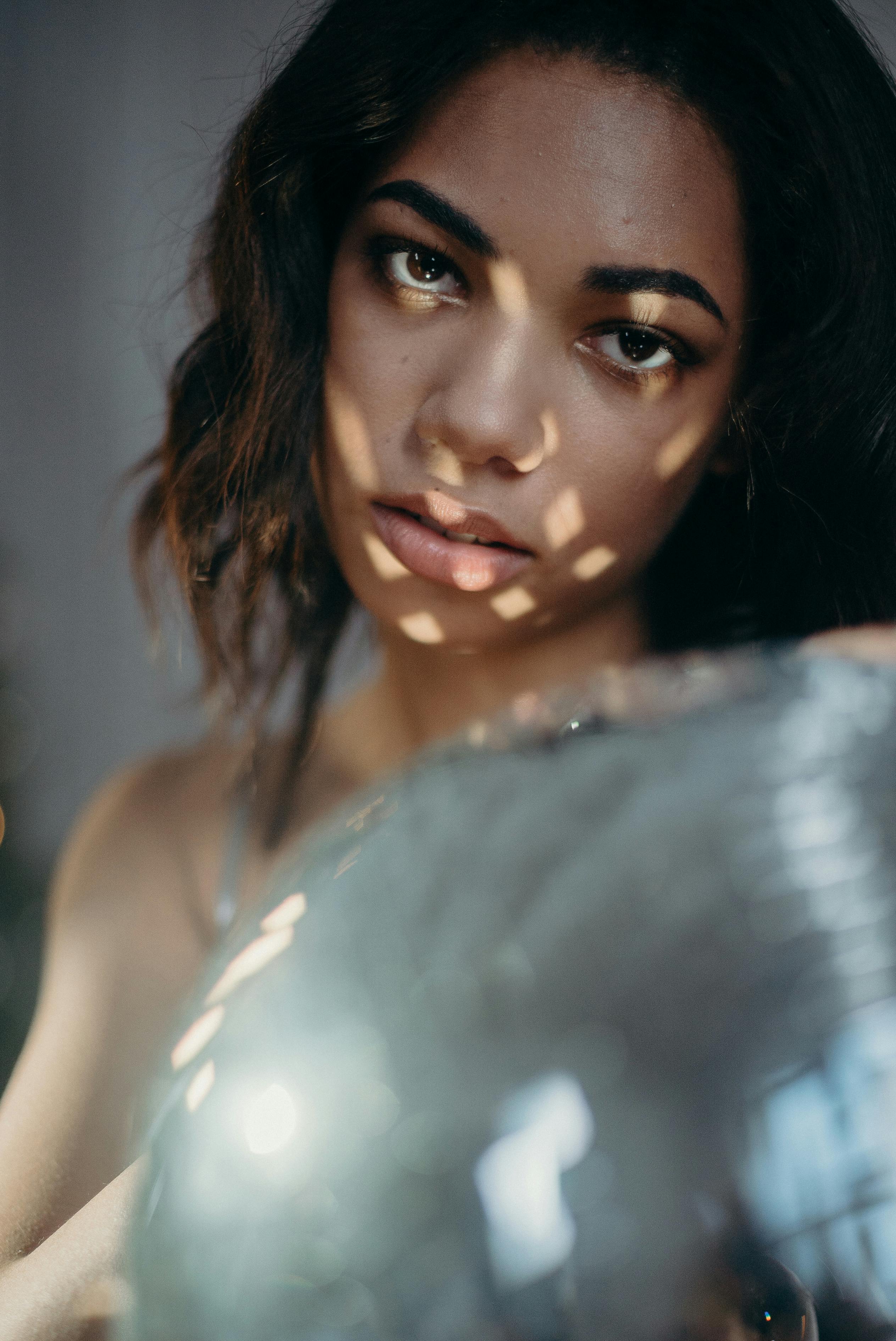 一位美丽的女人手持迪斯科球摆出姿势，灯光图案营造出令人着迷的氛围