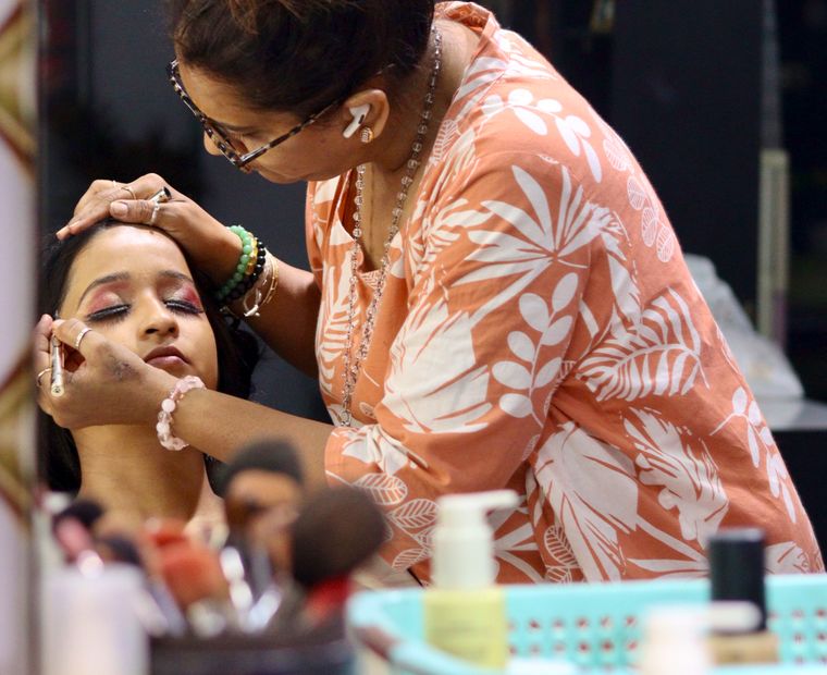 Beautician applying makeup to a seated client