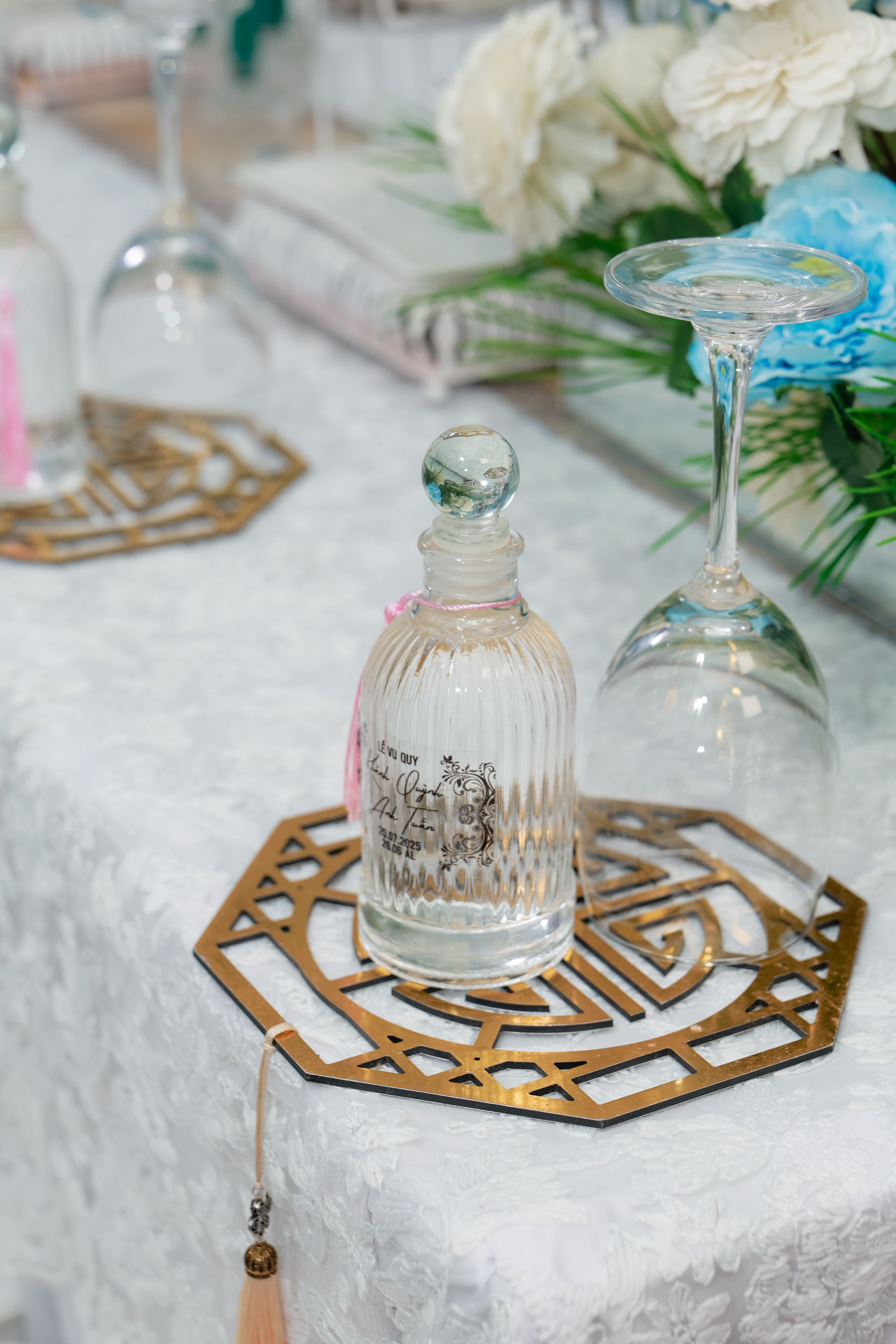 A sophisticated table setting featuring glass bottles, fancy coasters, and floral decor.
