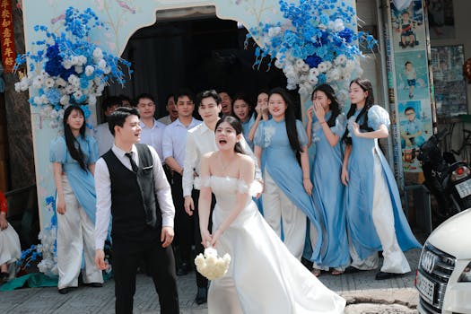 Bride and groom laughing with bridesmaids and groomsmen, outdoor wedding scene.