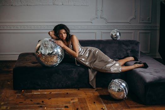 一位优雅的时装模特躺在配有迪斯科球的沙发上，置身于时髦的室内布景中