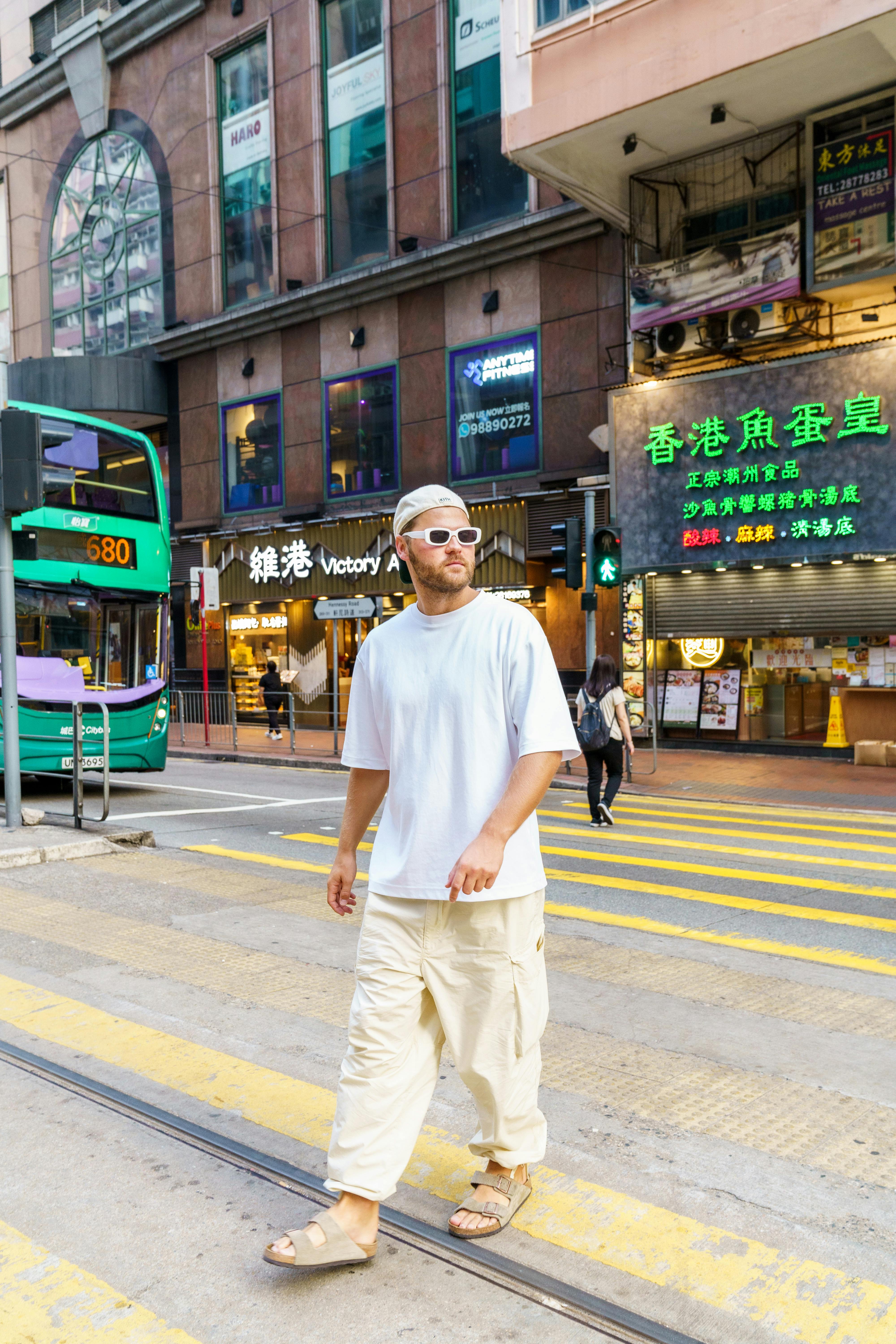Casually dressed man crossing a busy street in Hong Kong, vibrant city life.