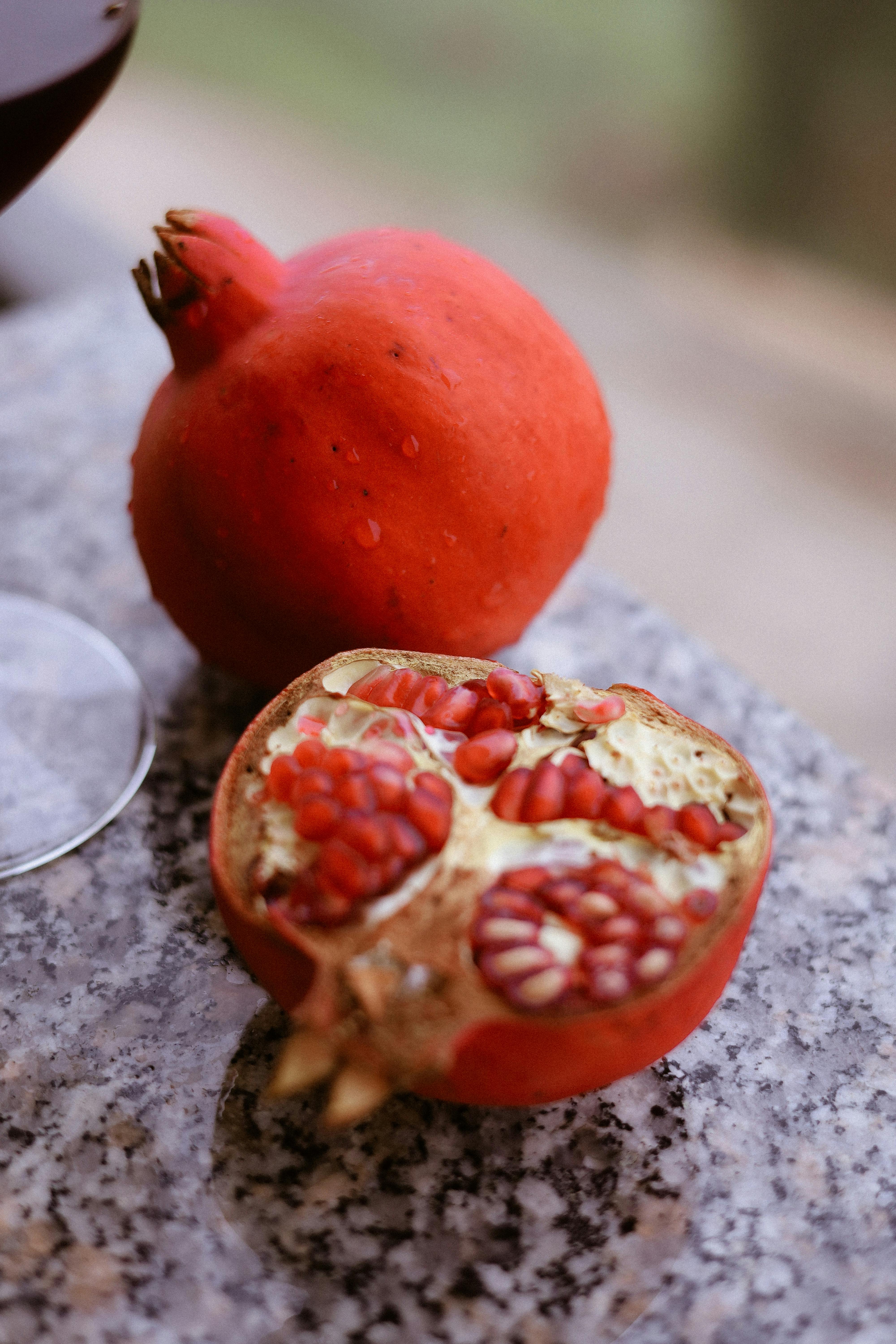 Vibrant red pomegranates displayed on a granite surface, showcasing their rich seeds.