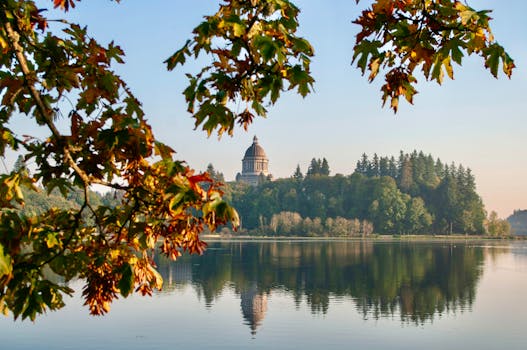 Scenic view of Olympia Capitol Building reflecting on water surrounded by autumn foliage.