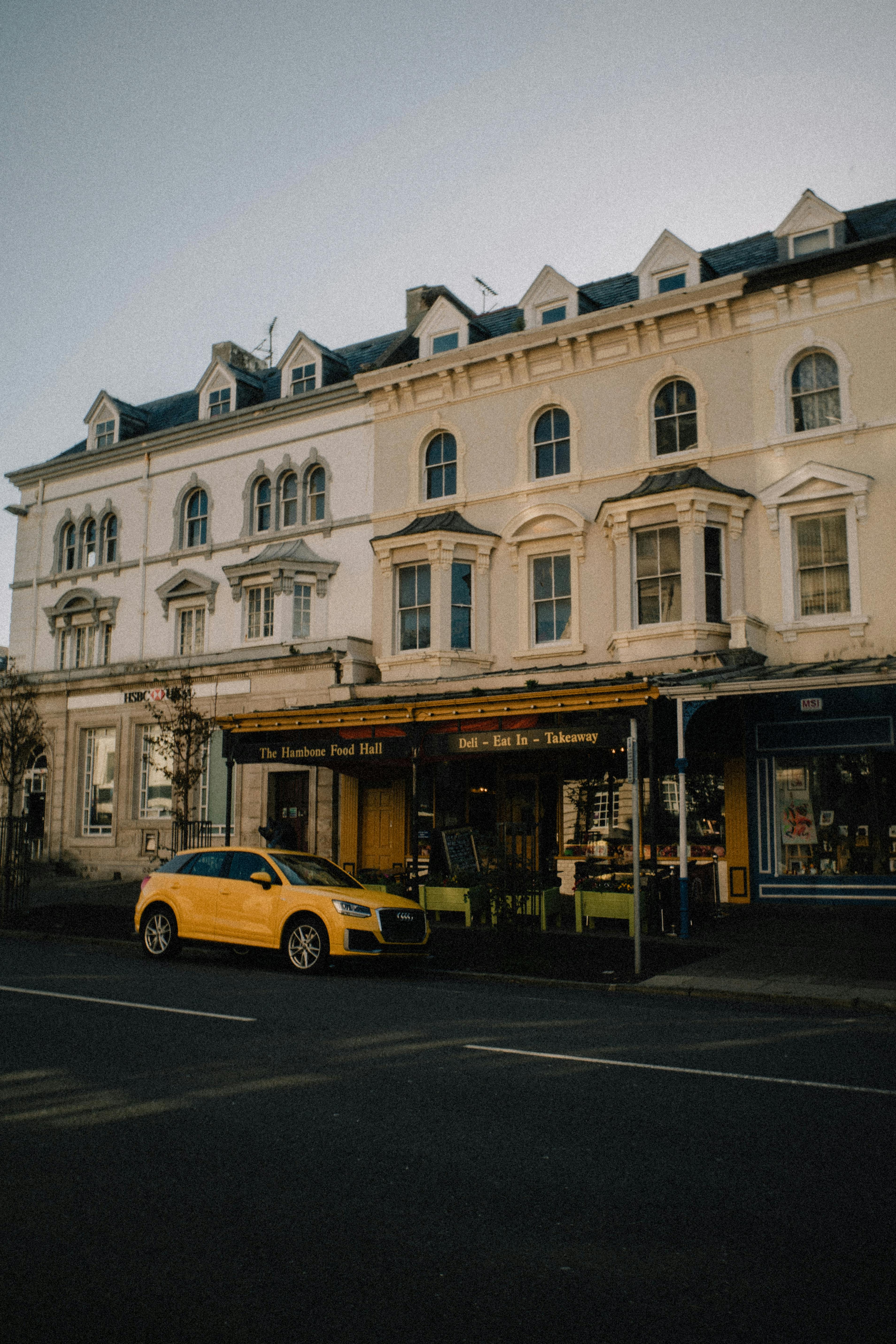 Yellow car parked on a street in front of historic buildings in Llandudno, Wales.