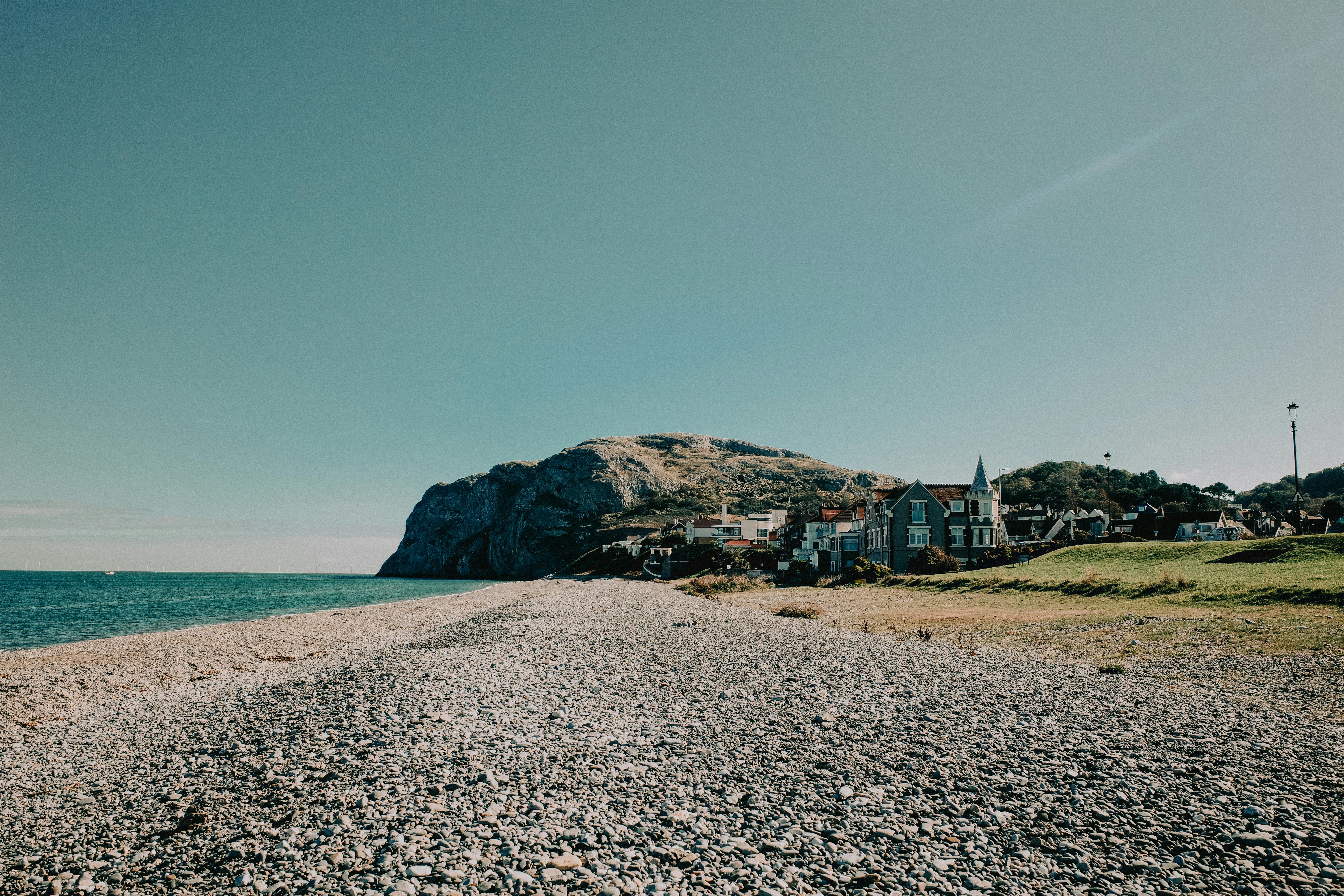 Pebble beach with hillside backdrop in Llandudno, Wales, showcasing coastal architecture and natural beauty.