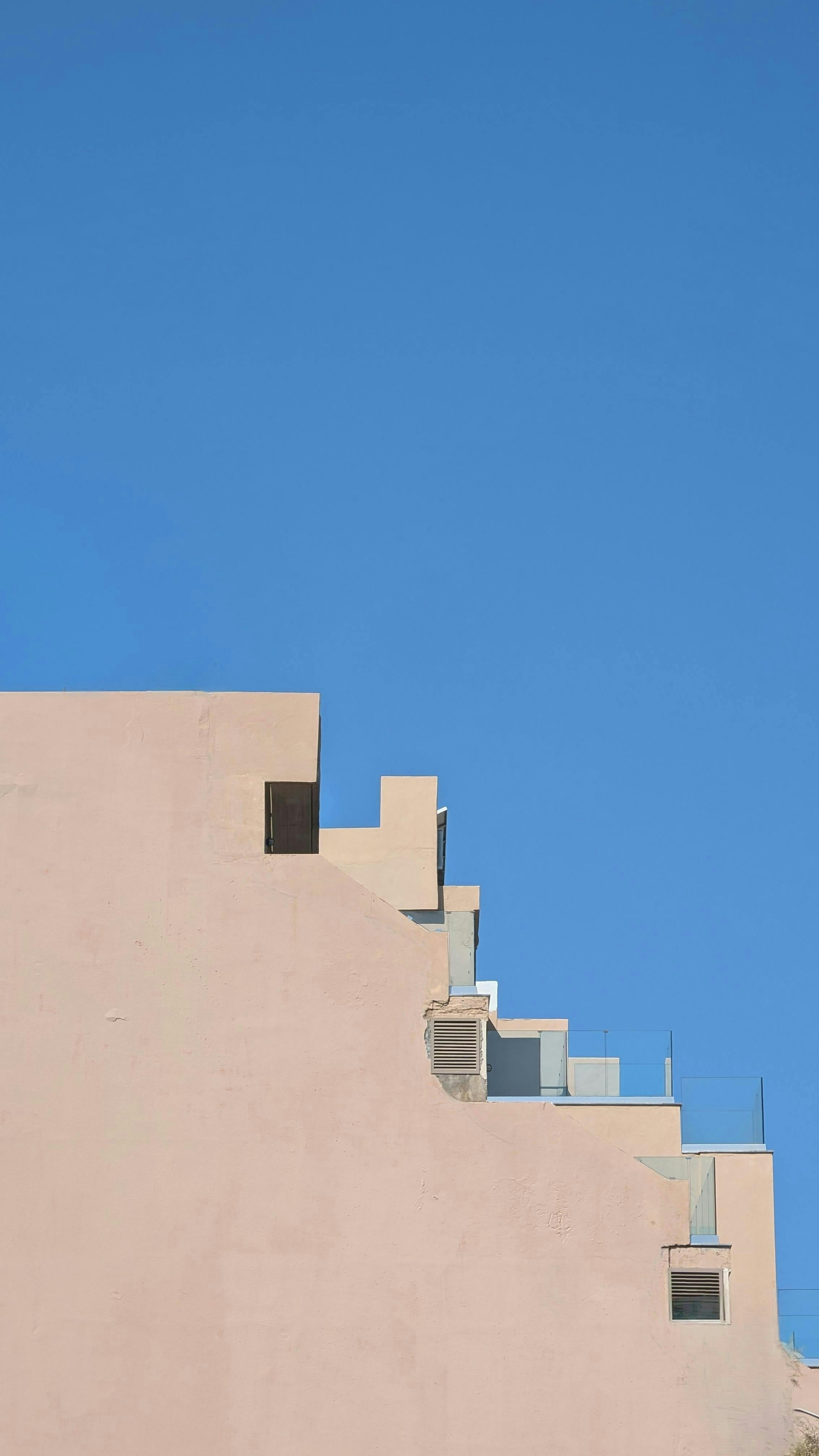 Minimalist architectural shot of a modern building facade in Rethymno, Greece with clear blue sky backdrop.